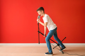Teenage boy with microphone singing against color wall © Pixel-Shot