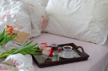 Coffee cup with book and colors  tulips in bed.