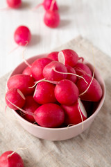 Fresh red radishes in a pink bowl, low angle view. Closeup.
