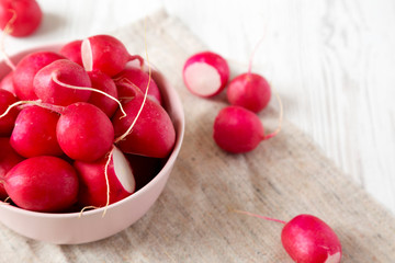 Fresh red radishes in a pink bowl, low angle view. Copy space.