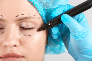 Plastic surgeon applying marking on female face, closeup
