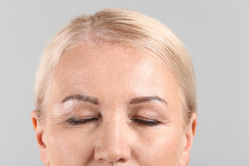 Mature woman on light background, closeup