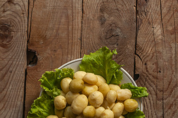 A plate of boiled new fresh potatoes on wooden background. Free space