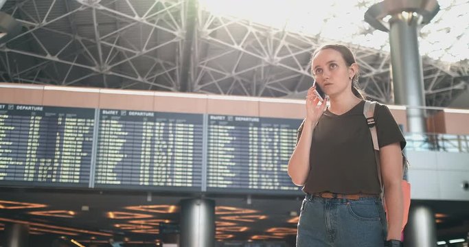 A woman at the airport on the phone discussing the delay of his flight
