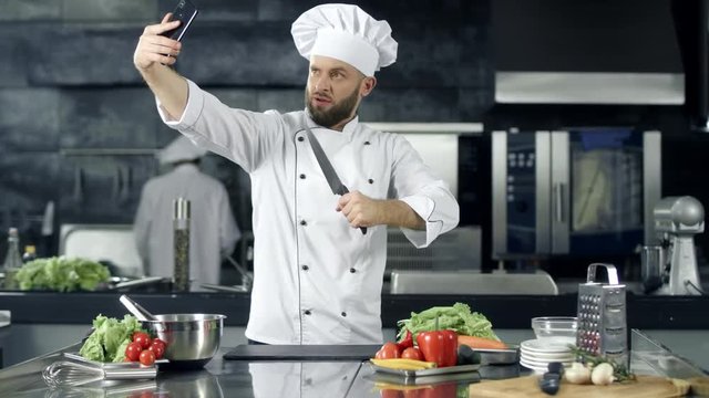 Male chef taking selfie photo at kitchen. Professional chef with knife