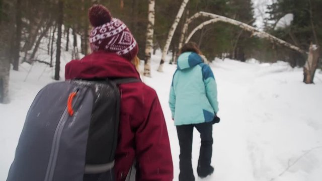 Woman backpacker in a winter hike snow forest trail national par Young girl enjoy snow falling . Happy winter holidays active lifestyle concept.