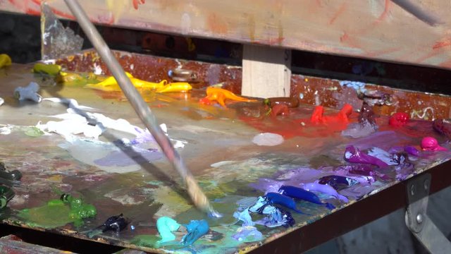 The Artist's Oil Palette. Mixing oil paint for painting. Blue, red, violet, purple colors