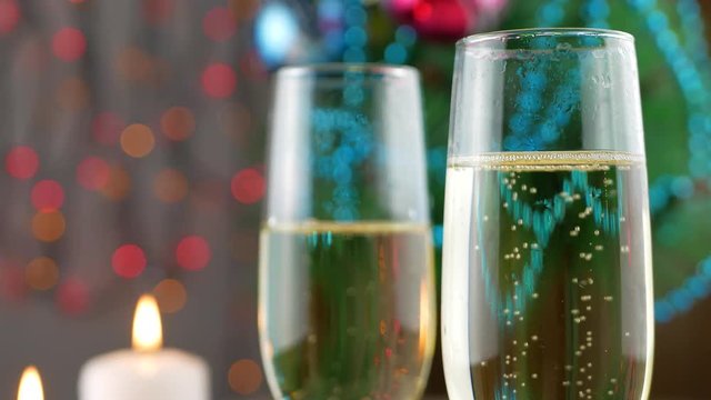 Champagne pouring and foaming in glasses over holiday bokeh green background. Success Christmas celebrating