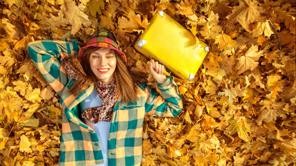 Happy autumn travel woman. Beautiful woman wearing bright clothes with yellow suitcase