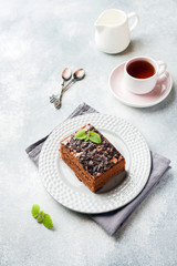 A piece of truffle cake with chocolate on a gray concrete background. Copy space