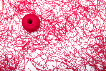 A ball of red thread and sewing needles on a white background
