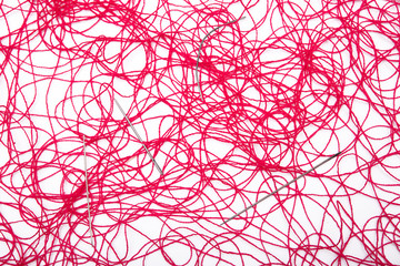 A ball of red thread and sewing needles on a white background