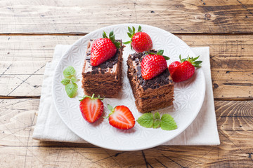 Chocolate truffle cake with strawberries and mint. Wooden table.