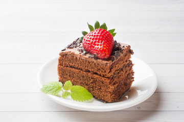 Truffle cake with chocolate and strawberries and mint on a white wooden table. Selective focus. Copy space