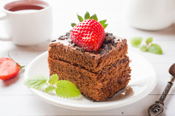 Truffle cake with chocolate and strawberries and mint on a white wooden table. Selective focus.