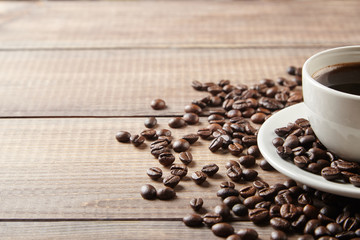 cup of coffee with beans on wooden table