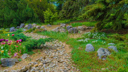 Rockery in the garden with stones and variety of different flowers and plants