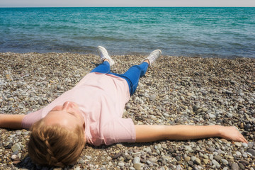 Cute girl lying on the beach making a snow angel