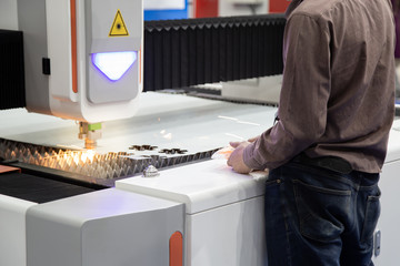 Industrial professional operate CNC laser cutting machine cutting metal sheet. Industrial...