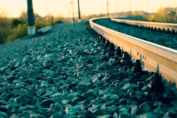 Railway. The rails curving in perspective go beyond the horizon. At sunset.