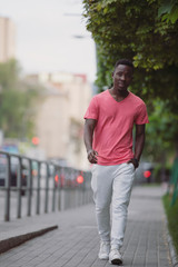 African american man in living coral t-shirt walking at city street, casual style