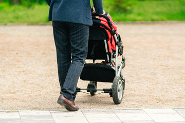 Obraz premium Walking businessman with baby carriage in the street.