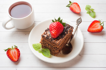 Truffle cake with chocolate and strawberries and mint on a white wooden table. Selective focus.