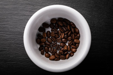 Coffee beans. Roasted coffee fries on a dark table.
