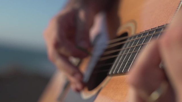 Man Playing and tuning acoustic Guitar Close Up shot side angle shot outdoor
