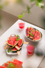 Fresh red smoothie in a glass with sliced pieces of watermelon on table.