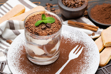 Classic tiramisu dessert in a glass on wooden background