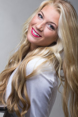 Beautiful blonde woman with red lipstick solo in studio with gray background