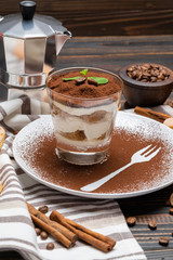 Classic tiramisu dessert in a glass on wooden background