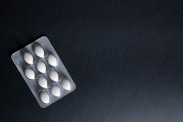 pills in blister on black background with copyspace