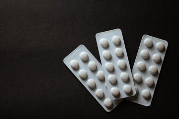 pills in blister on black background with copyspace