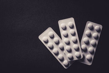 pills in blister on black background with copyspace