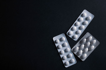 pills in blister on black background with copyspace