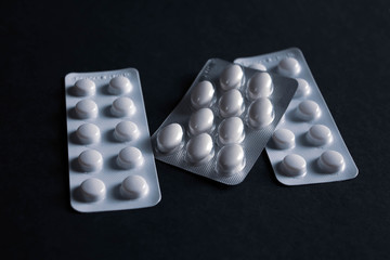 pills in blister on black background with copyspace