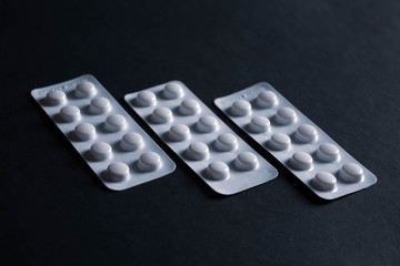 pills in blister on black background with copyspace