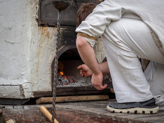 The cook prepares food on an outdoor antique wood-burning oven