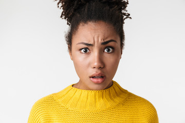 Beautiful young african confused woman posing isolated over white wall background.