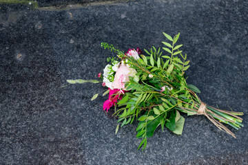 bouquet pink flowers on black marble gravestone