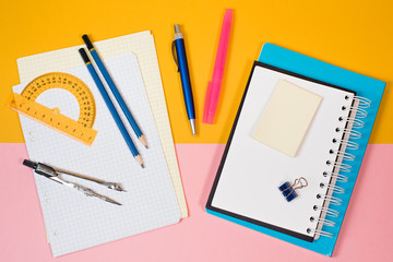 Back to school. Notebook, pencil case with pen and pencils on yellow and pink  background