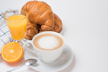 Breakfast coffee with croissants and orange juice on a white background. Latte on a saucer and cellular cotton towel