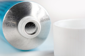 sealed tube of ointment cream on a white background with an open lid