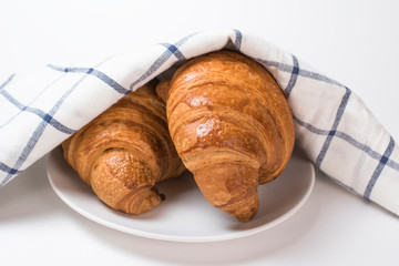 Breakfast croissants and checkered towel on a white background