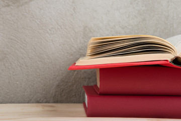 Education and reading concept - group of colorful books on the wooden table, concrete wall blackboard