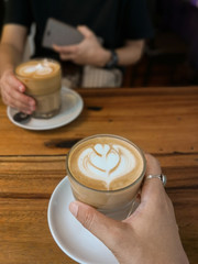 Female hands with coffee of glass on table.