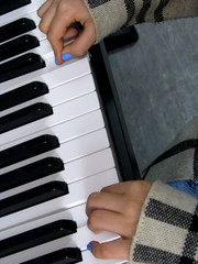 A young girl in a plaid coat plays an electronic piano (synthesizer)