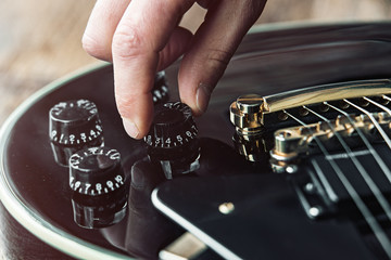 Male hand changing electric guitar settings. Tuning a timbre regulator